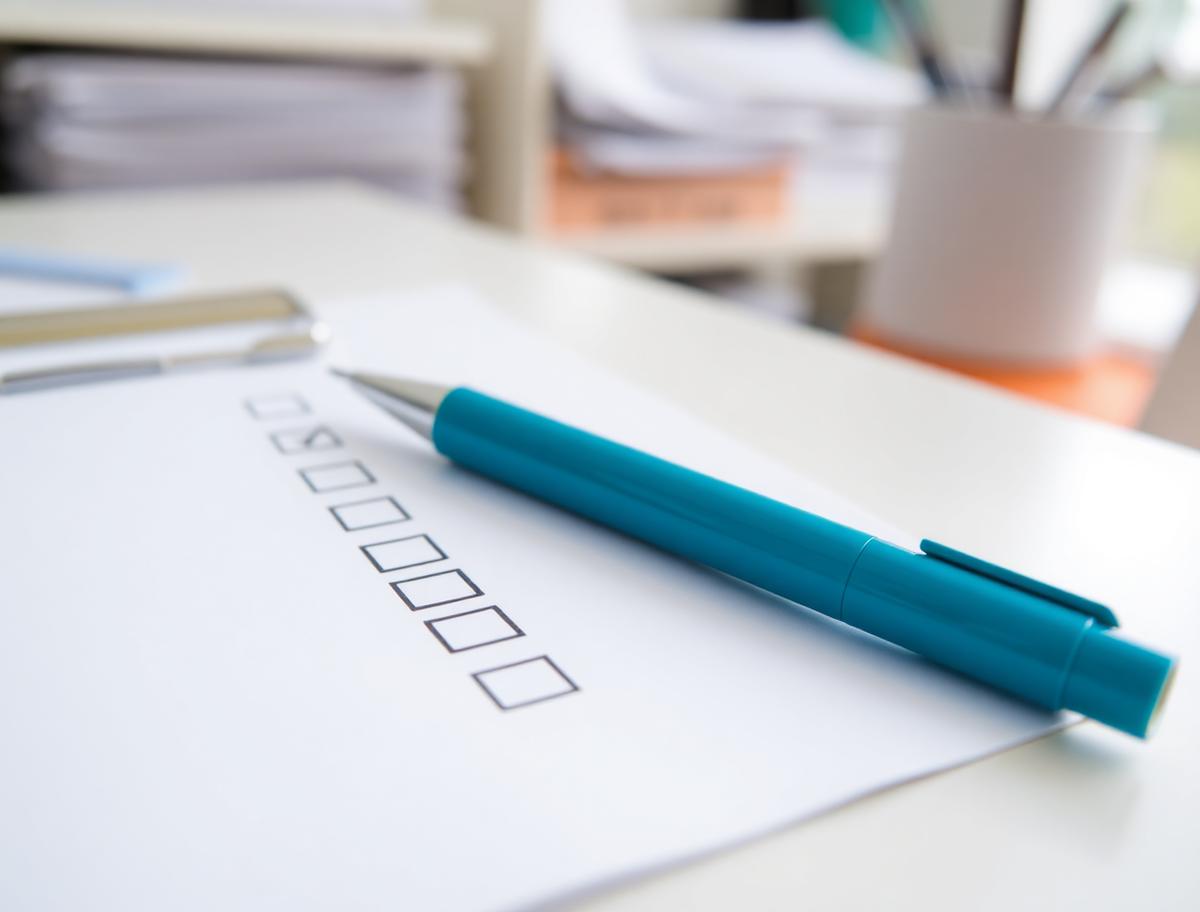 Printed checklist with ticked boxes and a teal pen